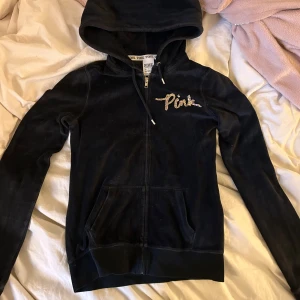 Svart hoodie från Pink - Snygg svart hoodie från Pink (Victorias secret) med glittrande paljettdetaljer på bröstet och ryggen. Den har en dragkedja framtill och en mysig huva. Lite y2k och mcbling beroende på hur den stylas, se defekt på 4e bilden 