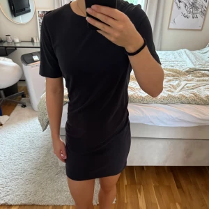 Svart t-shirtklänning från Monki - Enkel och stilren svart t-shirtklänning från Monki i mjuk bomull. Modellen är kort med rund halsringning och korta ärmar.🤍🌸