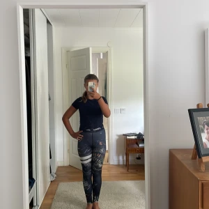 Mönstrade tights med hög midja - Säljer ett par snygga tights med hög midja och coolt abstrakt mönster i blått, vitt och orange. De är tighta och sitter skönt mot kroppen, perfekta för träning eller chill. Resår i midjan med textdetalj.