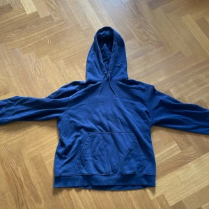 Blå hoodie från Weekday i bomull - Säljer en blå hoodie från Weekday i storlek M. Tröjan har en klassisk känguruficka, dragsko i huvan och är tillverkad i mjuk bomull. Perfekt för chill dagar eller när du vill ha en enkel och stilren look. Lägg ett bud om ni har ett pris förslag accepterar oftast.