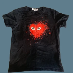 Svart Comme des Garçons Play t-shirt - Svart t-shirt från Comme des Garçons Play med ikoniskt rött hjärta med ögon på bröstet. Kortärmad modell i mjuk bomull, perfekt för en cool och avslappnad stil. Priset går att diskutera!! MVH