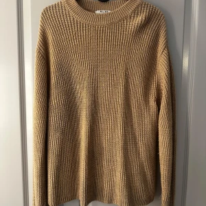 Beige stickad tröja från NA-KD - Säljer en beige stickad tröja från NA-KD i storlek S. Tröjan har en chunky ribbstickad struktur, rund halsringning och långa ärmar. 