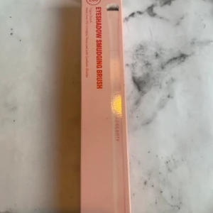 E05 Eyeshadow Smudging Brush - E05 Eyeshadow Smudging Brush med kompakt, kupolformad topp och täta, mjuka syntetiska strån. Perfekt för att sudda ut ögonskugga längs övre och undre fransraden. Handtag i FSC-certifierat trä och hylsa i återvunnet aluminium. Vegansk borste i ljusrosa förpackning.