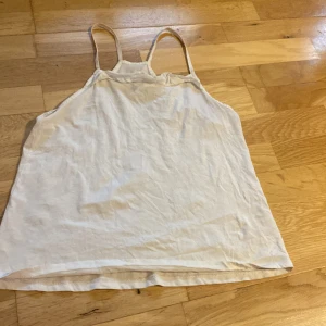 Vit linnetopp från Mango Kids - Enkel och stilren vit linnetopp från Mango Kids med tunna axelband och rak passform. Perfekt för varma dagar och lätt att matcha med jeans eller shorts. Tillverkad i mjuk bomull för en skön känsla.