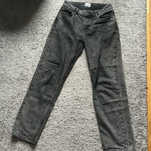 Svarta raka jeans från Grunt - Säljer ett par svarta jeans från Grunt med snygg tvättad look. Jeansen har raka ben, klassisk femficksmodell och bälteshällor. Materialet är jeans i bomull och de har en cool, lite sliten finish som ger en avslappnad vibe.