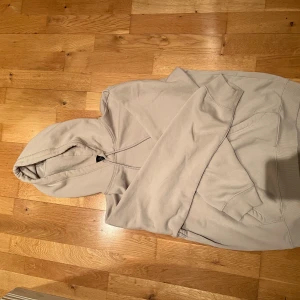 Beige hoodie från H&M Relaxed Fit - Säljer en beige hoodie från H&M i relaxed fit. Tröjan har huva med snörning och en stor magficka framtill. Perfekt för dig som gillar en enkel och clean stil. Materialet är mjukt och skönt, troligtvis bomullsmix. Passar till allt och är superbekväm.