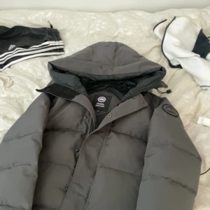 Grå Canada goose macmillan  - En grå macmillan jacka riktigt varm o skön till vintern ,inga defekter på jackan fjädrar ej och är väll omhändertagen så hör av er vid frågor (byten tas imot)