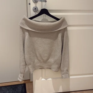 Beige offshoulder stickad tröja - Superfin beige stickad tröja med bred offshoulder-krage från hm. Mjuk och skön känsla, perfekt nu till hösten!Långärmad modell med ribbade muddar och avslut. Enkel att styla till jeans eller kjol💘 Den är lite nopprig men annars i fint skick och inget man tänker på💝