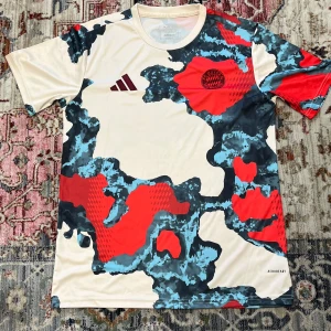 NY FC Bayern x Adidas Pre-Match tröja M - Unik Bayern München Pre-Match fotbollströja från Adidas. Tröjan har korta ärmar och ett färgstarkt camouflage-mönster i beige, rött, blått och svart. Tillverkad i lätt och ventilerande material med AEROREADY-teknologi. Perfekt för dig som vill sticka ut på planen.