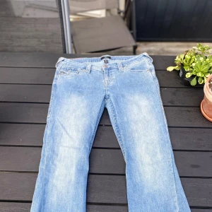 True Religion Joey Low Rise Flare jeans - Snygga ljusblå jeans från True Religion, modell Joey Low Rise Flare. De har låg midja, utsvängda ben och klassiska detaljer med dekorativa sömmar och knappar på bakfickorna. Dessa är i storlek 29 och har inte varit till användning. Kontakta mig för en mer genomgående kontroll eller för mer info!