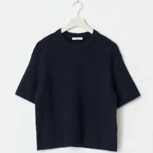 Mörkblå stickad tröja  - En stilren mörkblå stickad tröja från Gina Tricot med kort ärm och rund halsringning. Tröjan har en boxig, lite loose passform och är gjord i ett mjukt, stickat material som känns lyxigt och bekvämt. Perfekt för lager-på-lager och enkel att matcha. Mer bilder går att få! Den är lite nopprig!