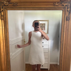 Vit ärmlös klänning med vågig kant - Supersöt vit kortklänning från H&M med vågiga kanter vid halsringning och ärmhål. Prislappen kvar och aldrig använd!