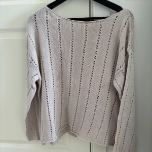 Ljusbeige stickad tröja med hålmönster - Superfin ljusbeige stickad tröja med lång ärm och snyggt hålmönster i ränder. Tröjan har en avslappnad passform och är perfekt för lager-på-lager under vår och höst. Enkel att matcha till både jeans och kjol.