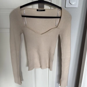 Beige ribbad tröja Gina Tricot - Supersnygg ribbad beige tröja från Gina Tricot med lång ärm och v-ringad halsringning. Tröjan har en figurnära passform och är tillverkad i mjukt stickat material. Perfekt inför höst!🍁