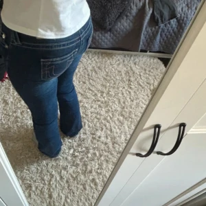 Blå True Religion jeans bootcut W25 - Säljer ett par blå jeans från True Religion med ikoniska bakfickor och kontrastsömmar. Modellen har bootcut-ben och klassisk femficksdesign. Jeansen är i stretchig denim som sitter snyggt och bekvämt. Perfekta för dig som gillar en tidlös och cool look.