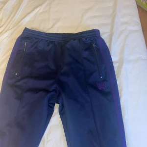 Blå trackpants från Needles - Säljer ett par needles trackpants i storlek S, passar både tjejer och killar. Straight i passformen. Använt skick, liten defekt på baksidan av byxorna (se bild 4) och även lite noppriga men går att fixa till ;). Säljer byxorna för att de Alldrig används längre och är för små. Vid minsta fråga, pris eller fler bilder, hojta till:)
