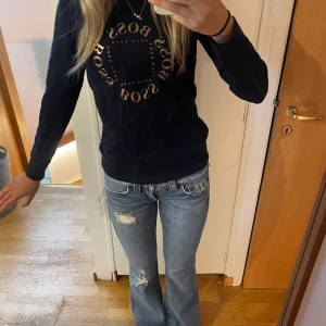 Marinblå långärmad tröja från Hugo Boss - Marinblå långärmad tröja från Hugo Boss med rosé logga i cirkel på bröstet. Klassisk passform och rund halsringning, perfekt till jeans eller kjol. Mjuk och skön bomullskänsla, enkel att styla för en cool vardagslook. Storlek 14-S jag skulle uppskatta den till xs