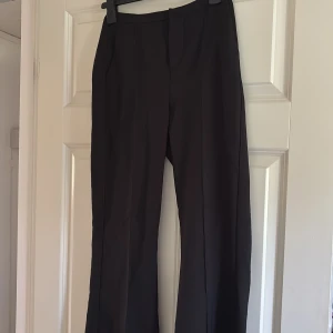 Svarta kostymbyxor med bootcut - Snygga svarta kostymbyxor med bootcut och pressveck. Byxorna har en klassisk look med raka ben som blir vidare nertill. Perfekta att styla med sneakers eller boots för en clean vibe från ginatricot