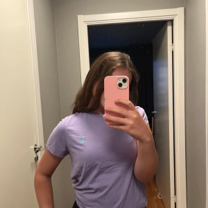 Lila t-shirt från Polo Ralph Lauren - Säljer en lila t-shirt från Polo Ralph Lauren med klassisk passform och korta ärmar. T-shirten har en broderad turkos logga på bröstet och är gjord i mjuk bomull. Perfekt basic-plagg med snygg färg som lyfter din outfit. Den står M, med den sitter som en XS/S. Jag själv har S och den sitter jättebra. 