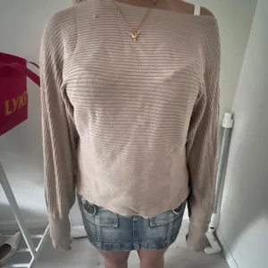 Beige ribbad långärmad tröja - Säljer en beige ribbad tröja med lång ärm och avslappnad passform. Tröjan har tunna horisontella ränder och är tillverkad i ett mjukt material som känns skönt mot huden. Perfekt för dig som gillar en enkel och stilren look.