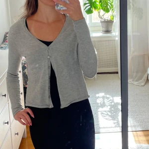 Ljusgrå kofta från Vero Moda - Jättefin ljusgrå kofta från Vero Moda i storlek XS. Koftan har en v-ringning och små knappar framtill. Kontakta om du har frågor💕
