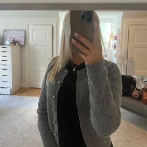 Grå kofta från Zara med pärlknappar - Superfin grå kofta från Zara med snygga pärlknappar framtill. Koftan är stickad och har lång ärm, perfekt att slänga över en topp. Enkel och stilren modell som passar till många outfits.