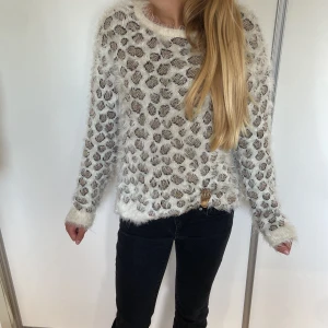 Snygg leopard tröja  - Supermjuk och fluffig långärmad tröja med leopardmönster i beige, brunt och vitt. Tröjan har rund halsringning och är stickad med lurvigt garn som ger en cool och mysig look. Perfekt för dig som vill sticka ut med ett djurmönster och gillar trendiga vibes.