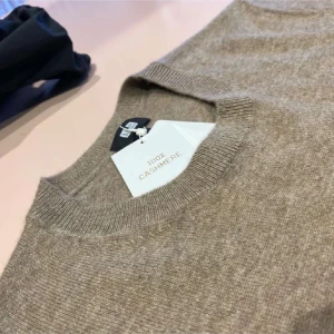 Beige kashmirtröja från Uniqlo - Säljer en stilren beige tröja i 100% kashmir från Uniqlo. Tröjan har en klassisk rund hals och långa ärmar med ribbade muddar. Perfekt för en elegant och bekväm look.