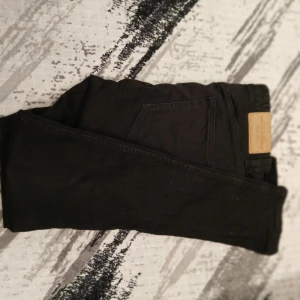 Svarta jeansbyxor - Snygga svarta jeansbyxor med klassisk design. De har en normal passform och är perfekta för en stilren look. Byxorna har en dragkedja och knappar framtill. Storlek w31 L32