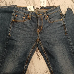 Blå jeans från Rocket - Snygga blå jeans från Rocket med klassisk femficksdesign och kontrastsömmar. Perfekta för en avslappnad stil. Märkeslapp i läder baktill.