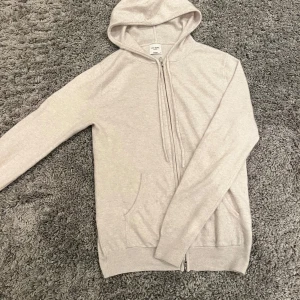 Kashmir hoodie John Henric - Säljer en stilren beige hoodie från John Henric. Den har dragkedja framtill och en praktisk huva med snörning. Tröjan är i bra skick och i 100% cashmere extrem skön och varm! Ny pris 2500! Byten intressant Den är i bergige/ vit! 