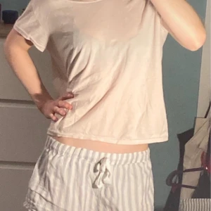 Ljusrosa pyjamastopp  - Säljer en enkel och bekväm beige t-shirt med korta ärmar. Perfekt för en avslappnad stil. T-shirten har en lös passform och är tillverkad i ett mjukt material.