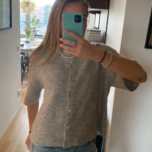 Grå kofta från Gina Tricot - Säljer en mysig grå kofta från Gina Tricot i storlek M. Koftan har en ribbad struktur och knappar framtill. Perfekt för kyliga dagar och lätt att matcha med olika outfits.