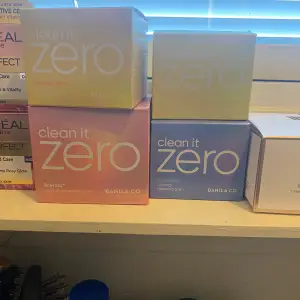 Clean It Zero Cleansing Balm från Banila Co i olika varianter. Förpackningarna har olika färger som rosa, blå och gul, vilket indikerar olika egenskaper som original, calming och glow. Perfekt för att effektivt ta bort smink och rengöra huden. 100 st