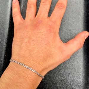 Silverfärgat armband med tvinnad design - Snyggt silverfärgat armband med en elegant tvinnad design. Armbandet har en smidig karbinhake för enkel på- och avtagning. Perfekt för att ge en stilren touch till din outfit.