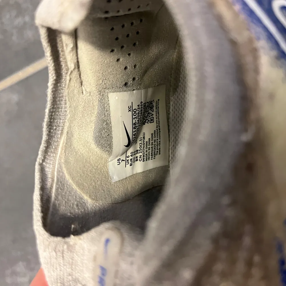 Säljer ett par Nike Mercurial fotbollsskor i beige med blå detaljer. Skorna har en strömlinjeformad design med en blå Nike-logga på sidan och orange detaljer på sulan. Perfekta för snabba rörelser på planen. Skorna har inga defekter utom lite smuts som är svår borttaget. . Kengät.
