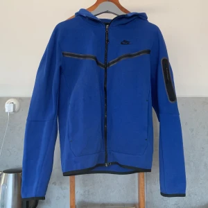 Blå Nike Tech Fleece - En Blå Nike tech fleece. Den har tecken på användning som man ser på bilderna men är inte särskilt urtvättad. Hör av er om ni har en fråga angående tröjan😊
