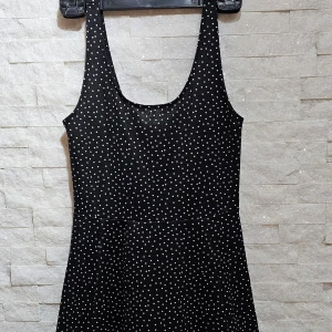 Svart prickig klänning från Divided - Snygg svart klänning med vita prickar från Divided. Klänningen har en ärmlös design och en rundad halslinje. Perfekt för en stilren look med en touch av lekfullhet.