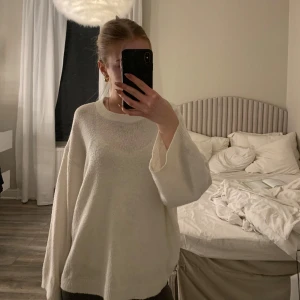 Vit stickad tröja - Säljer en mysig vit stickad tröja med långa ärmar och rund hals. Perfekt för kyliga dagar och enkel att matcha med olika outfits. Passar både till jeans och kjol.