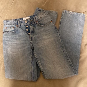 Blå jeans från Zara - Säljer ett par klassiska blå jeans från Zara. De har en rak passform och är högmidjade med knappgylf. Perfekta för en avslappnad stil.💕