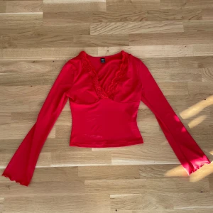 Röd långärmad topp från Shein - Snygg röd topp från Shein med långa ärmar och v-ringning dekorerad med spets. Perfekt för en trendig look. Materialet är mjukt och stretchigt för en bekväm passform.