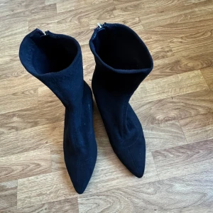 Svarta stövletter med dragkedja - Snygga svarta stövletter med spetsig tå och dragkedja bak. Perfekta för en stilren look. De har en elegant design som passar till många olika outfits.