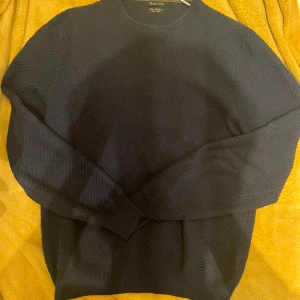 Mörkblå tröja från Massimo Dutti - Säljer en stilren svart tröja från Massimo Dutti i en mjuk bomull- och kashmirblandning. Tröjan har en klassisk design med rund hals och långa ärmar, perfekt för en elegant look.