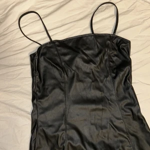 Svart klänning från Hm - Snygg svart klänning från Divided med smala axelband och en figurnära passform. Perfekt för en kväll ute eller en speciell tillställning. Klänningen har en stilren design som framhäver din siluett.