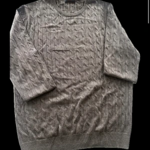 Brun stickad tröja från Morris - Säljer en stilren brun stickad tröja från Morris med ett diskret mönster och broderad logga på bröstet. Tröjan har långa ärmar och rund halsringning. Perfekt för en avslappnad och snygg look.