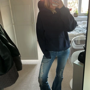 Mörkblå hoodie - Säljer en mörkblå hoodie med en klassisk design. Den har en stor ficka framtill och en huva. Perfekt för en avslappnad stil.