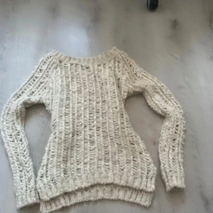 Beige stickad tröja - Säljer en mysig beige stickad tröja med ett luftigt mönster. Tröjan har långa ärmar och ribbade kanter vid ärmslut och nederkant. Perfekt för sommardagar och även strand besök!
