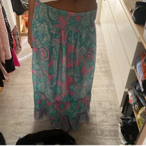 Mönstrad långkjol i turkos och rosa - Säljer en färgglad långkjol med ett livligt mönster i turkos och rosa. Kjolen har en elastisk midja för en bekväm passform och är perfekt för sommarens varma dagar. Den är luftig och lätt, vilket gör den idealisk för en avslappnad stil. Passar xs-m (ej jag på bilden)