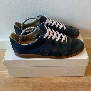 Mörkblåa Maison Margiela  - Säljer ett par snygga unika mörkblå Maison Margielas med storlek  44. Skorna är en äldre modell som inte säljs mer vilket gör dem unika. Box, OG snören och dustbags medföljer. Skorna är i bra skick men har en liten sliten undersula. Skriv gärna vid minsta fundering 