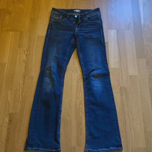 Mörkblå bootcut jeans - Snygga mörkblå bootcut jeans med klassisk femficksdesign och knappgylf. Perfekta för en avslappnad stil. Passar bra till både sneakers och klackar.